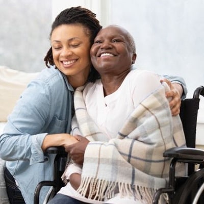 Caregiver embracing an older woman at home